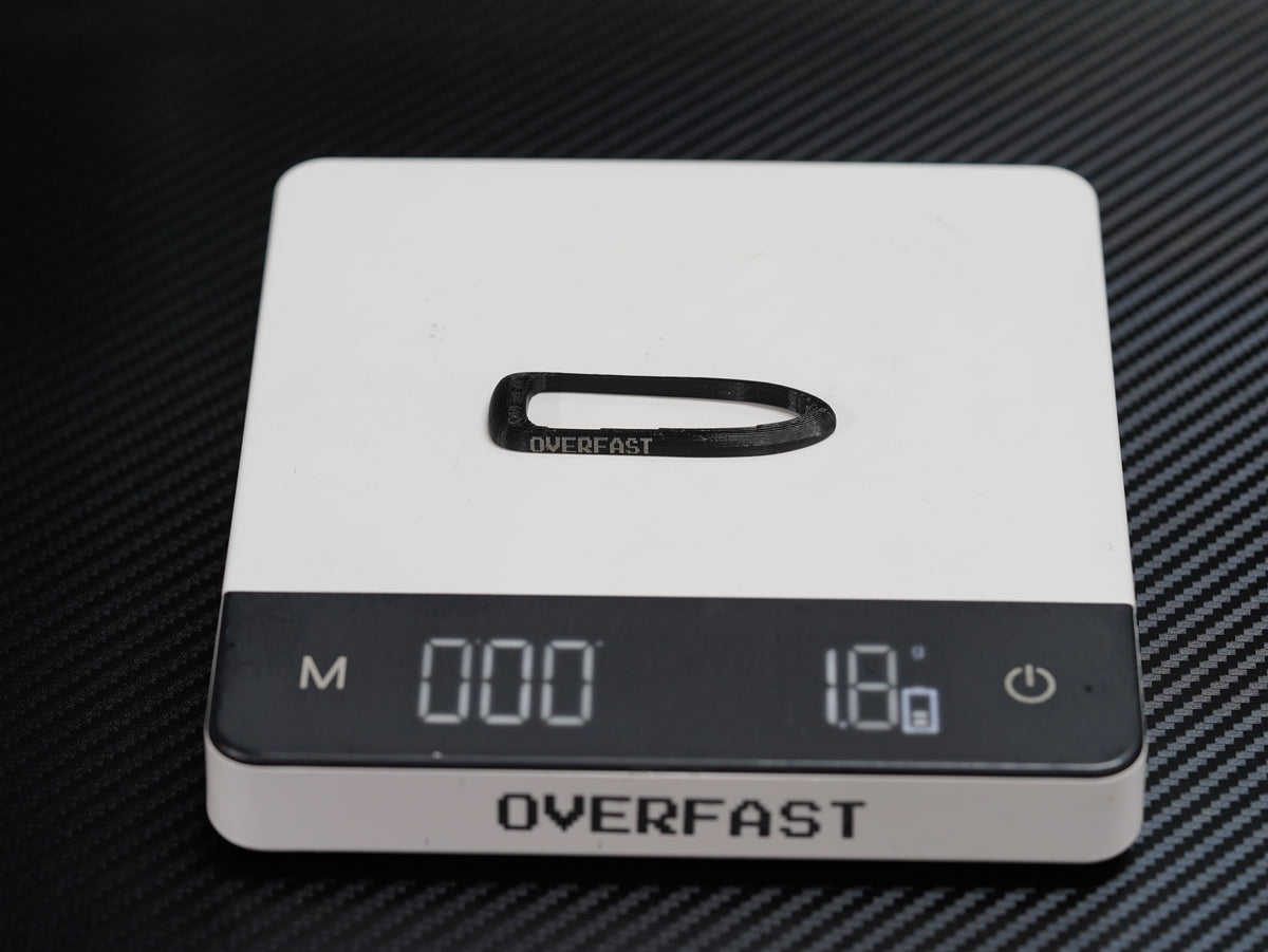 A white and black digital pocket scale with an LCD display screen, shown on a dark textured background. The brand name 'OVERFAST' is clearly visible on the front of the scale.