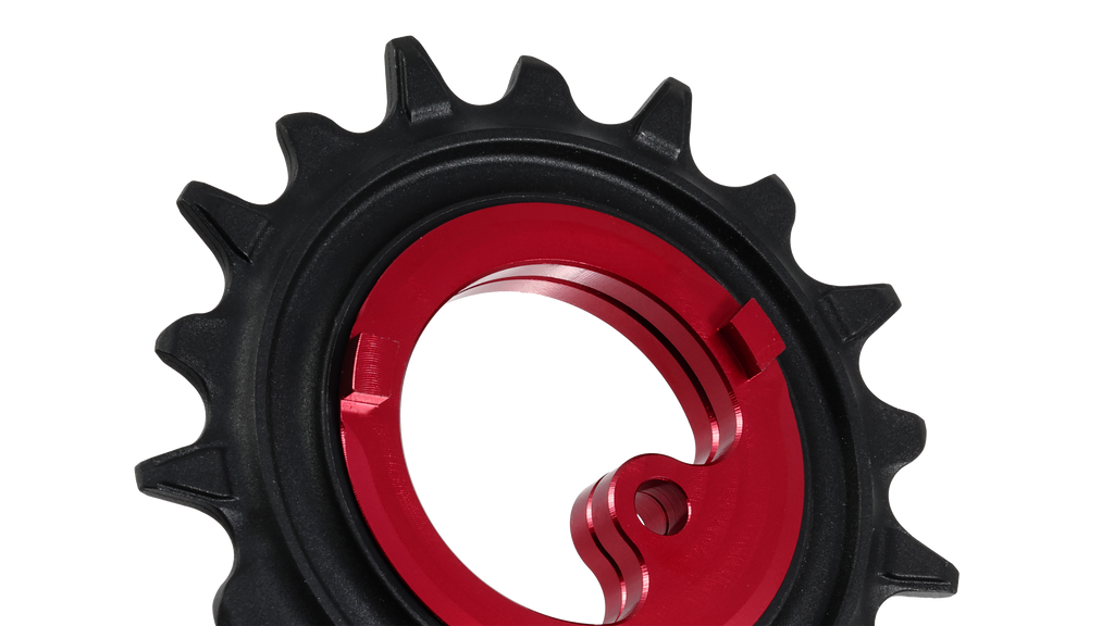 A close-up of a bicycle chainring with a black outer sprocket and a bright red inner ring, shown on a plain white background.