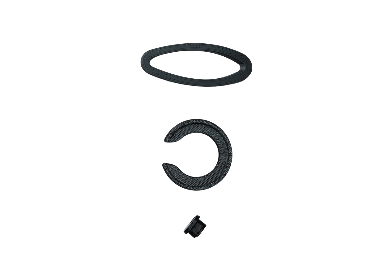 Three black replacement parts, including a flat oval ring, a textured C-shaped spacer, and a small cylindrical component, arranged vertically on a plain white background.