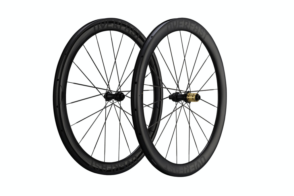 Two black carbon fiber road bicycle wheels with thin spokes and a gold hub accent, shown against a solid white background.