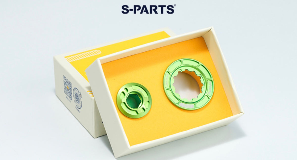 Two green circular mechanical parts displayed inside an open white box with a yellow insert, with the S-PARTS logo above on a light gray background.