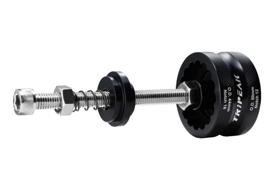 A metal and black mechanical tool with a threaded rod, hex nut, spring, and two circular end pieces, one of which is black and printed with the brand name 'TRIPEAK'.