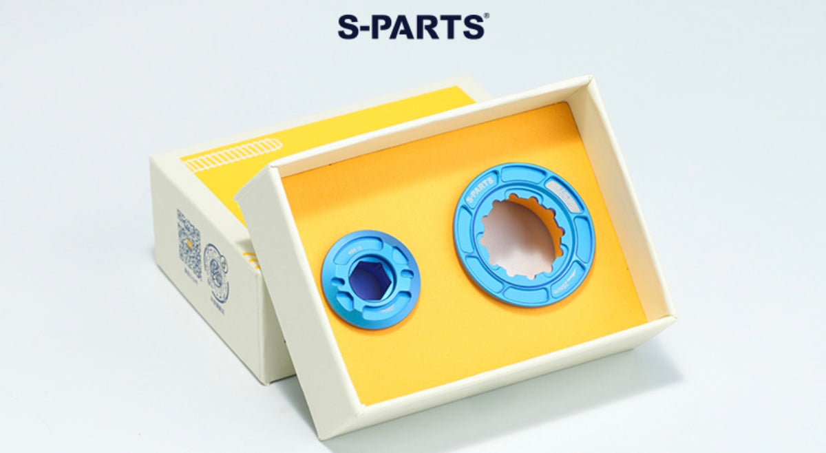Two blue circular mechanical parts displayed inside an open cream-colored box with a yellow insert, with the brand name S-PARTS printed above on a light gray background.
