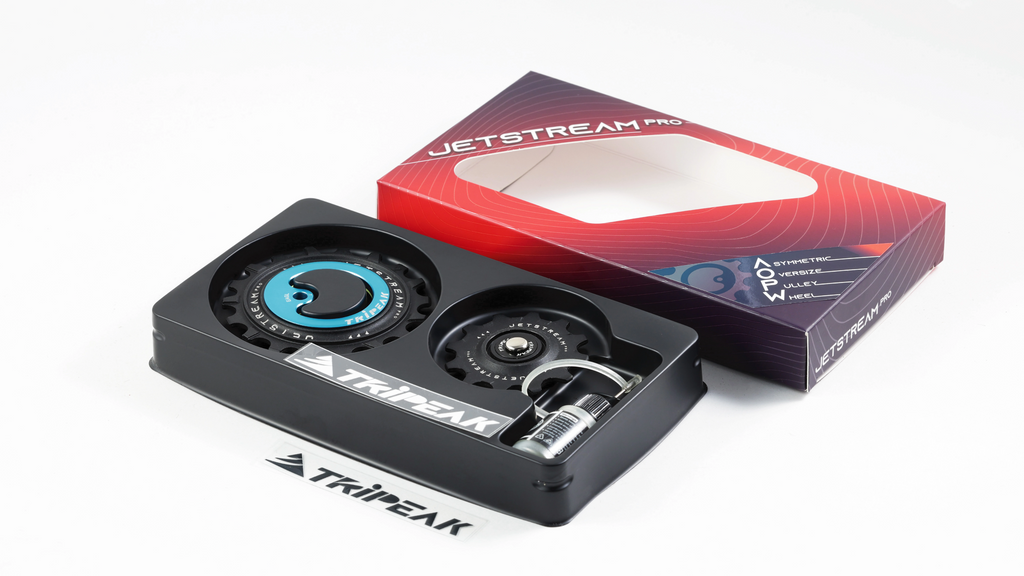 A black Tripeak Jetstream Pro snowmobile valve cover with a blue accent ring and a clear valve, shown next to its red and purple retail box on a white background.